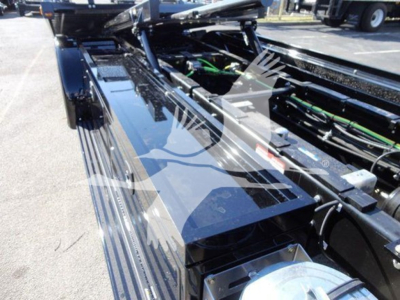 Truck cab and hydraulic lines of a 2022 International MV rollback chassis showing glossy black paint and green hoses.