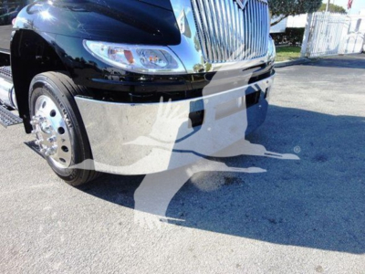 Truck front end and front left wheel of a 2022 International MV rollback truck showing chrome grille, headlight, and bumper.