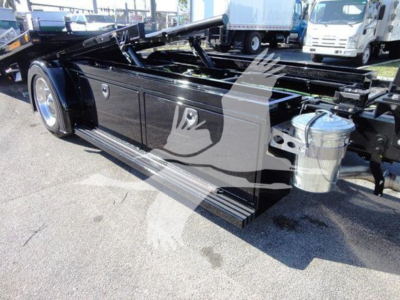 International MV rollback truck chassis side view showing black toolbox, long frame, chrome fuel tank, and dual rear wheels.