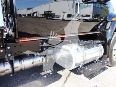 Truck side view showing chrome cylindrical fuel tank and step plate on a black International MV rollback truck.