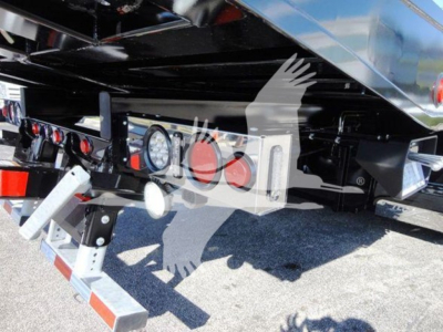 Truck undercarriage showing rear bumper, hitch, and license-plate mount with lights and hydraulic components.