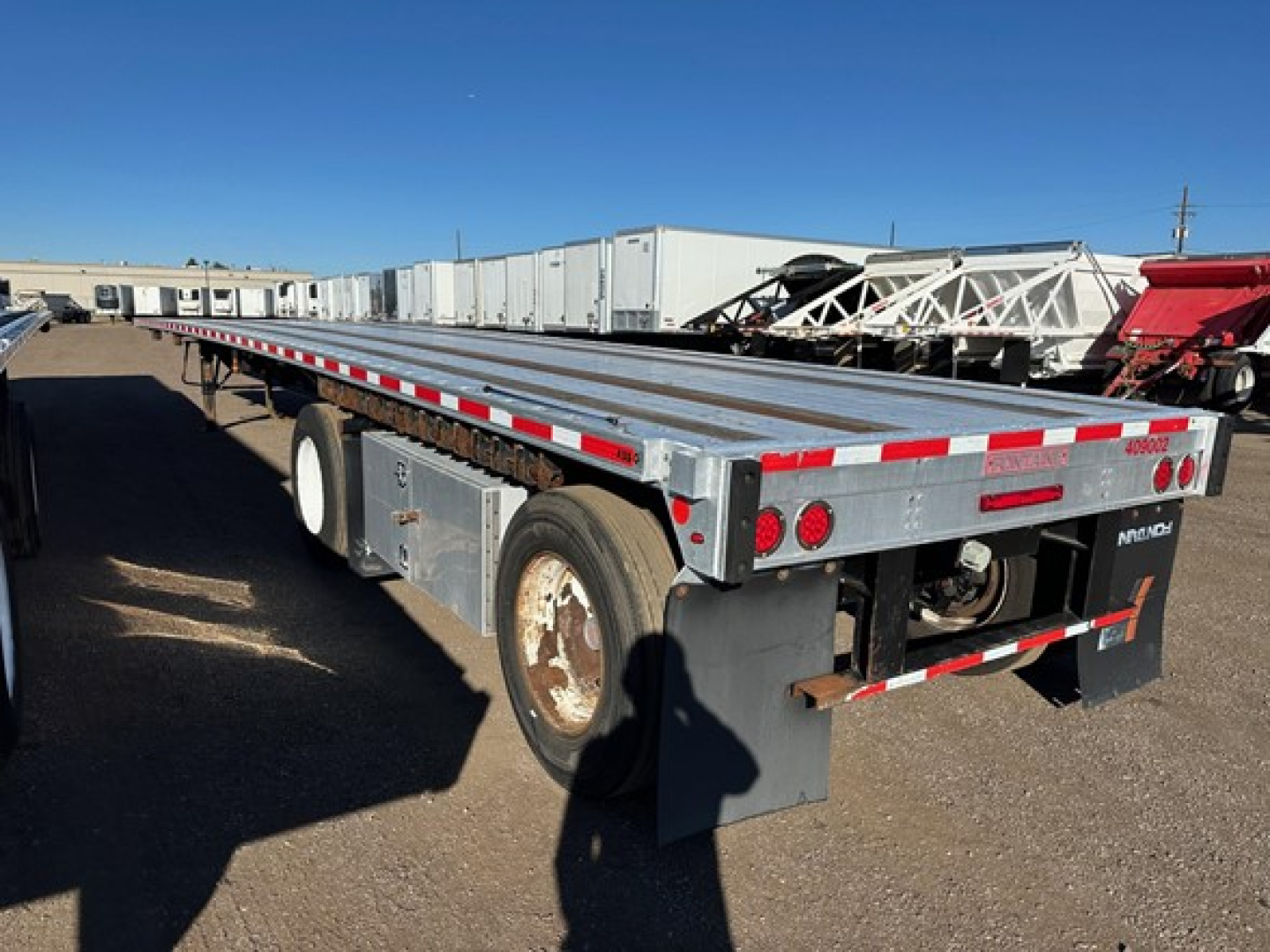 Flatbed trailer showing aluminum deck with reflective tape and rear bumper lights
