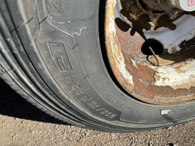 Trailer tire and rusty wheel hub showing worn outer edge and rim with rust, part of Fontaine Infinity trailer in a flatbed unit.