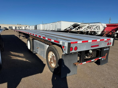 Flatbed trailer showing aluminum deck with reflective tape and rear bumper lights