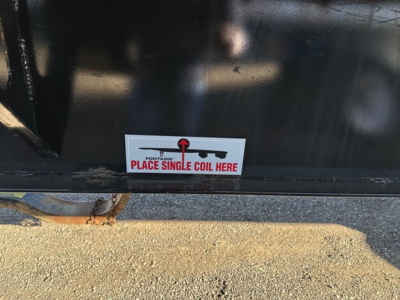 Label on Fontaine Infinity trailer showing 'PLACE SINGLE COIL HERE' with schematic arrows, mounted on black metal surface near lower edge.
