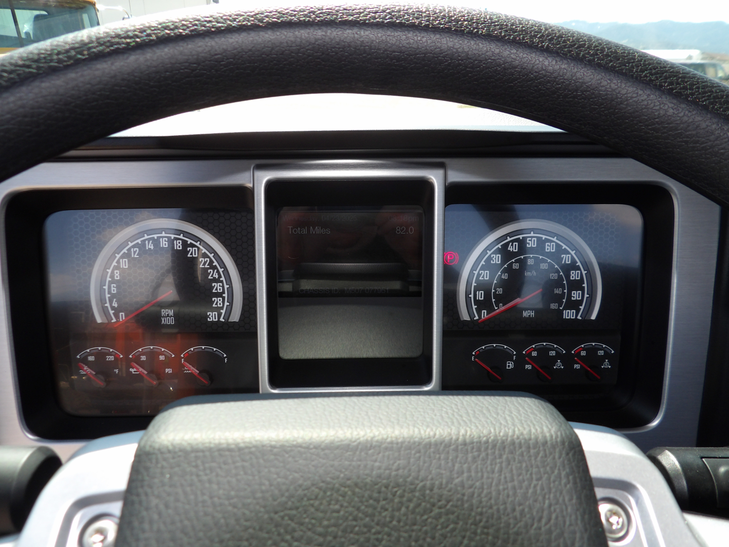 Dashboard view of a 2026 Mack MD7 from the driver's seat. Instrument cluster with speedometer and tachometer, center display screen, steering wheel, various gauges visible.