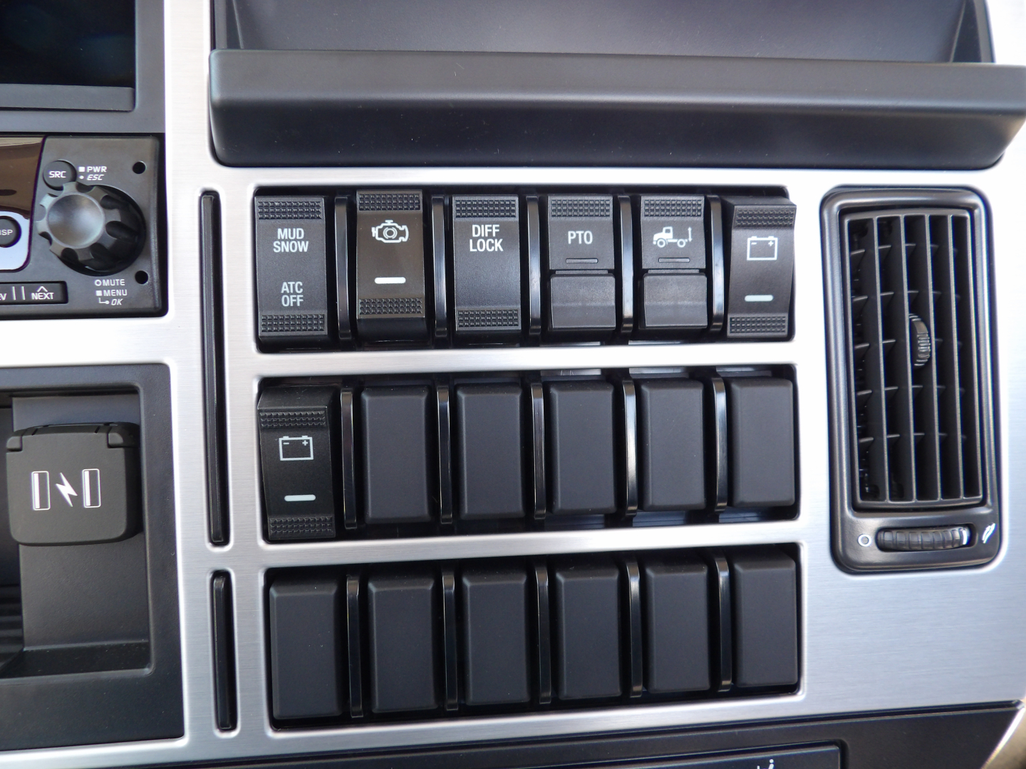 Dashboard area of a 2026 Mack MD7 showing multiple switches labeled diff lock, PTO, mud/snow, ATC off, and other controls.