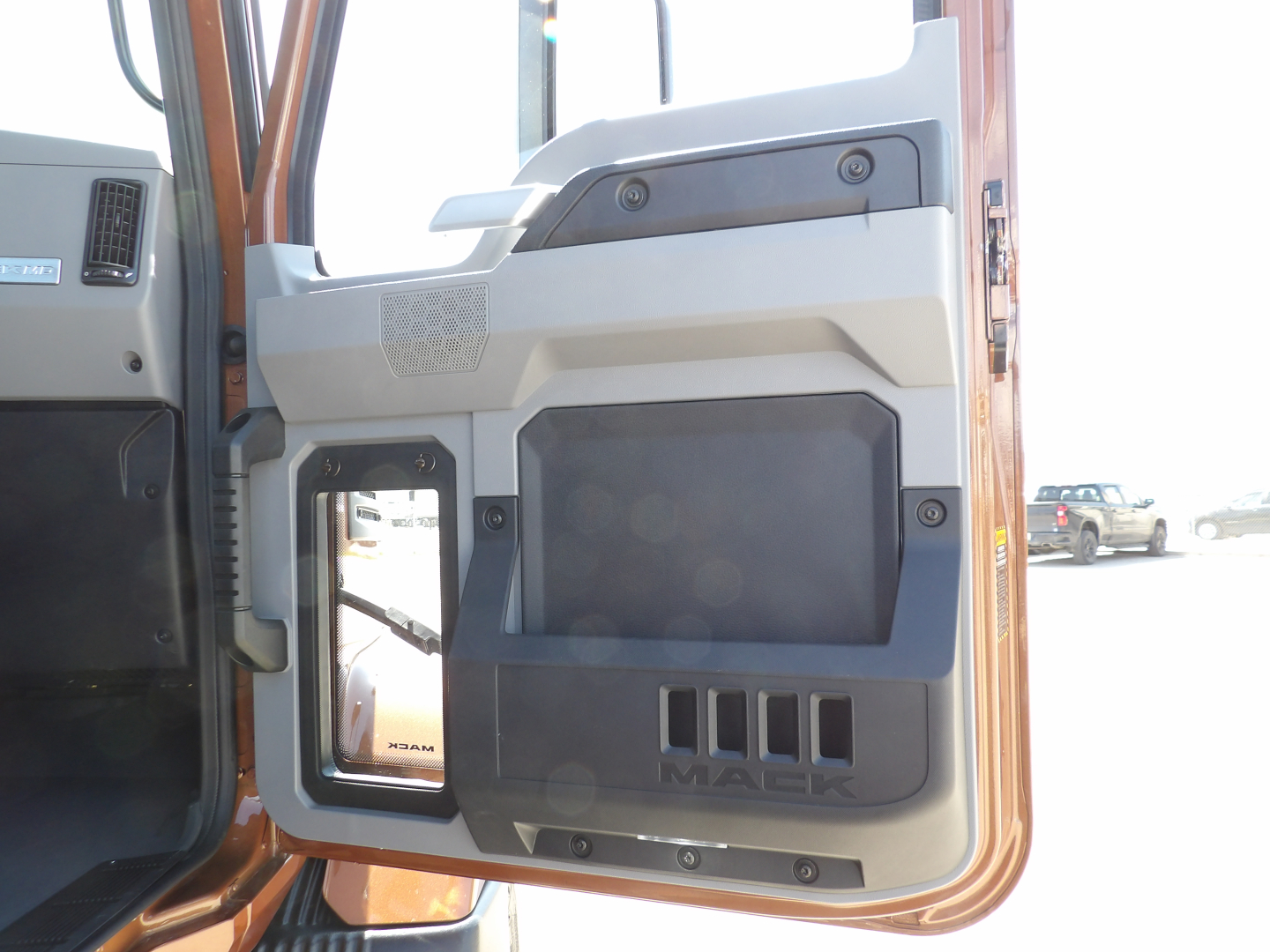 Truck door interior panel of a 2026 Mack MD7 dump truck showing beige/gray door trim and control area with MAkE logo and vents.