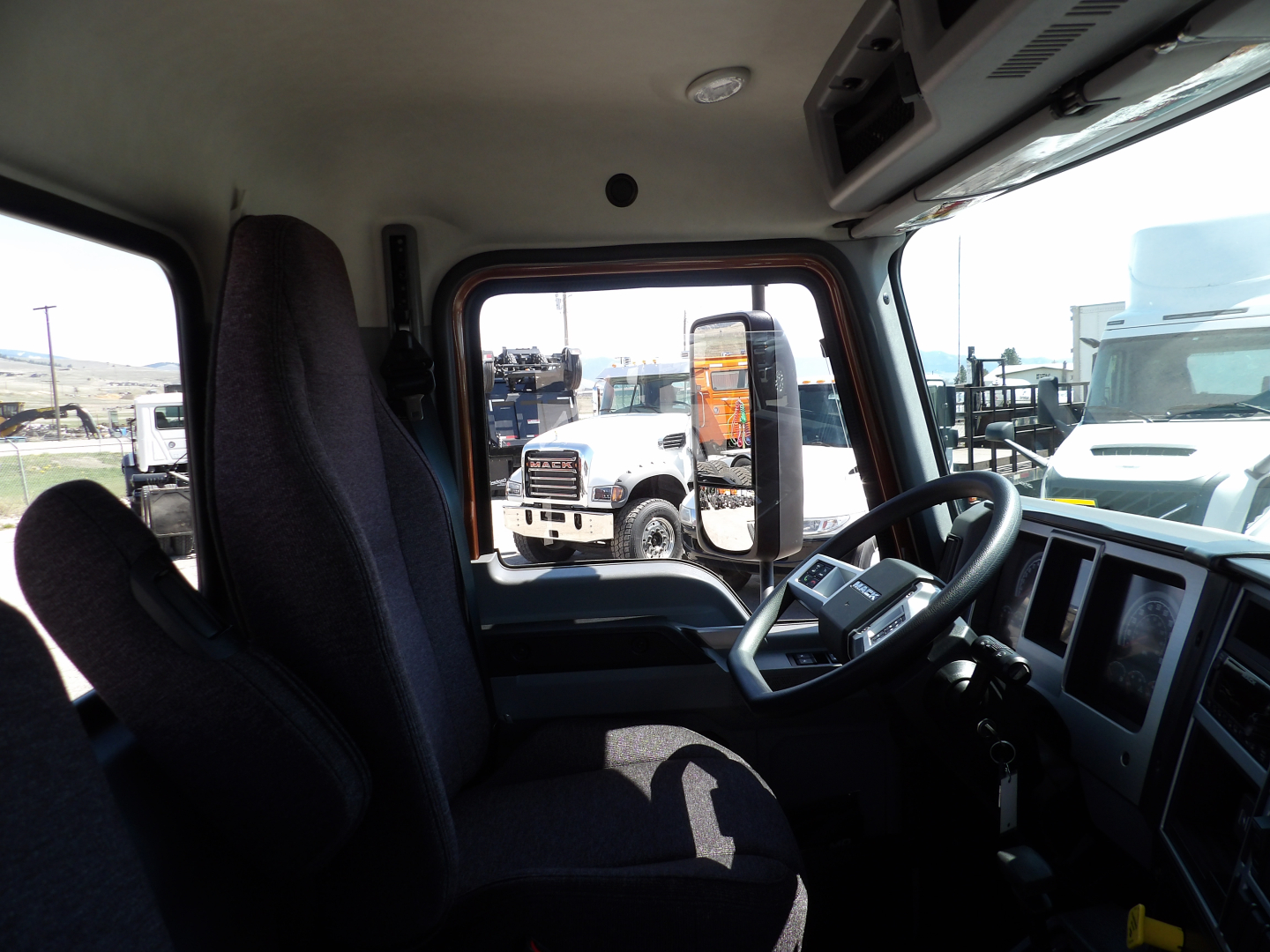 Cab interior of a 2026 Mack MD7 dump truck showing steering wheel, dashboard, and seats.