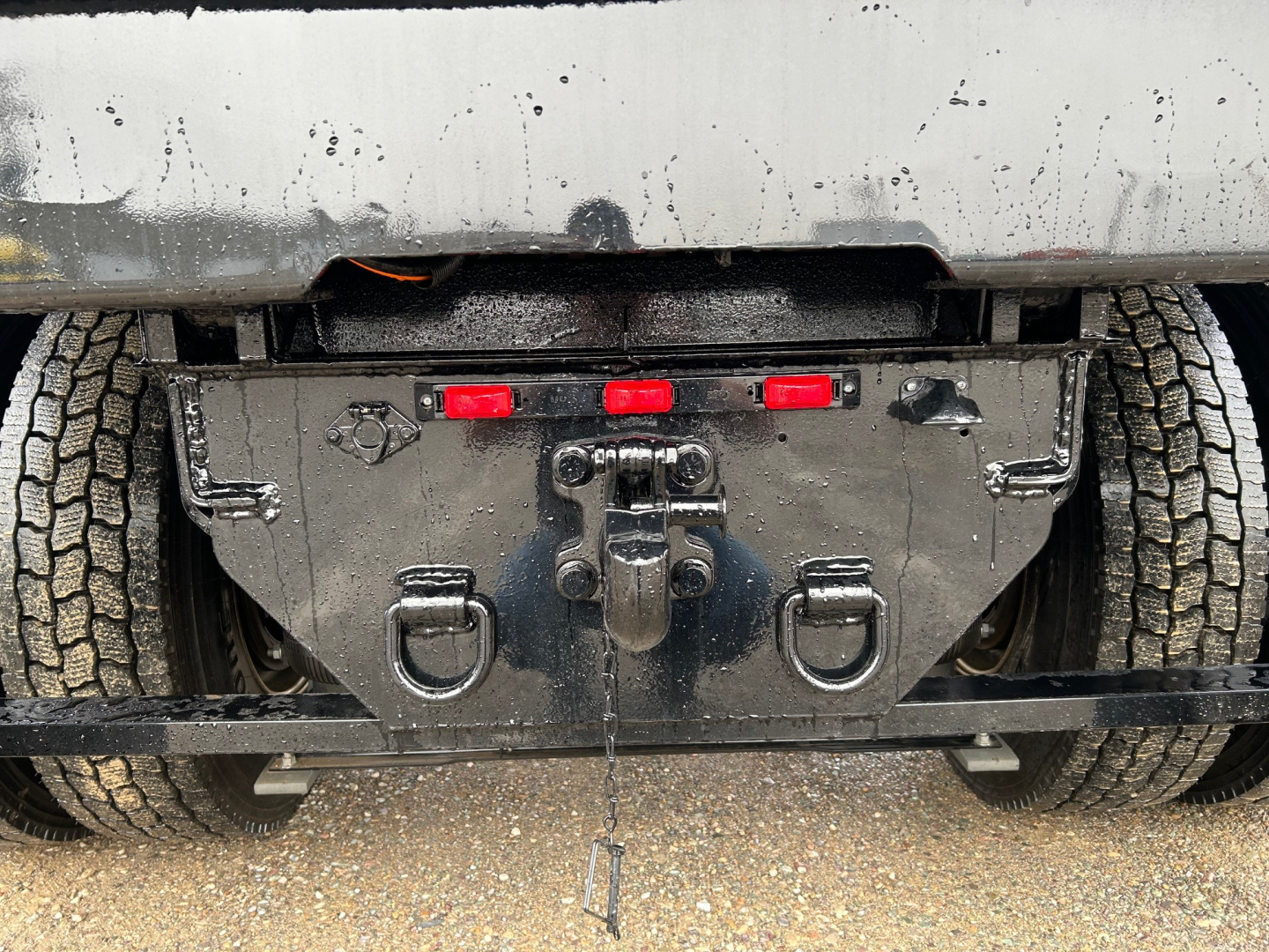 Rear view of a new Mack MD7 dump truck showing underbody equipment and hitch assembly.