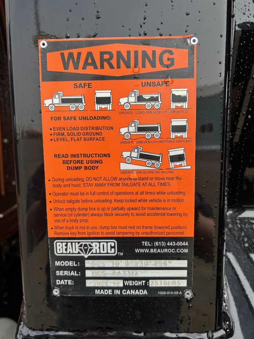 Warning label on Mack MD7 dump truck component showing safe unloading instructions and pictograms.