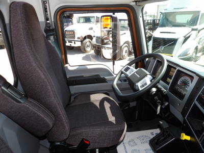 Cab interior of a 2026 Mack MD7 dump truck showing driver seat and steering wheel with dashboard and gear lever.