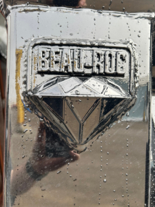 Bealloc chrome emblem on Mack truck MD7 hood with water droplets and diamond logo.