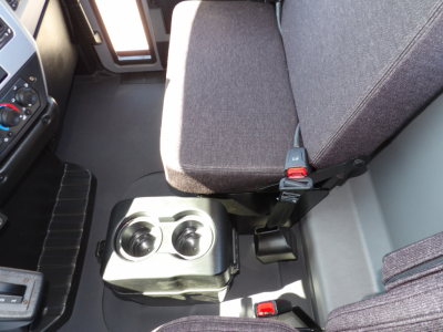 Truck cab interior showing driver seat and center console with two cup holders and seat belt buckles in a Mack MD7 cab.