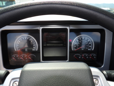 Dashboard view of a 2026 Mack MD7 from the driver's seat. Instrument cluster with speedometer and tachometer, center display screen, steering wheel, various gauges visible.