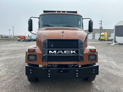 Front view of a brown 2026 Mack MD7 dump truck showing large black grille with MACK letters, headlights, and front bumper.