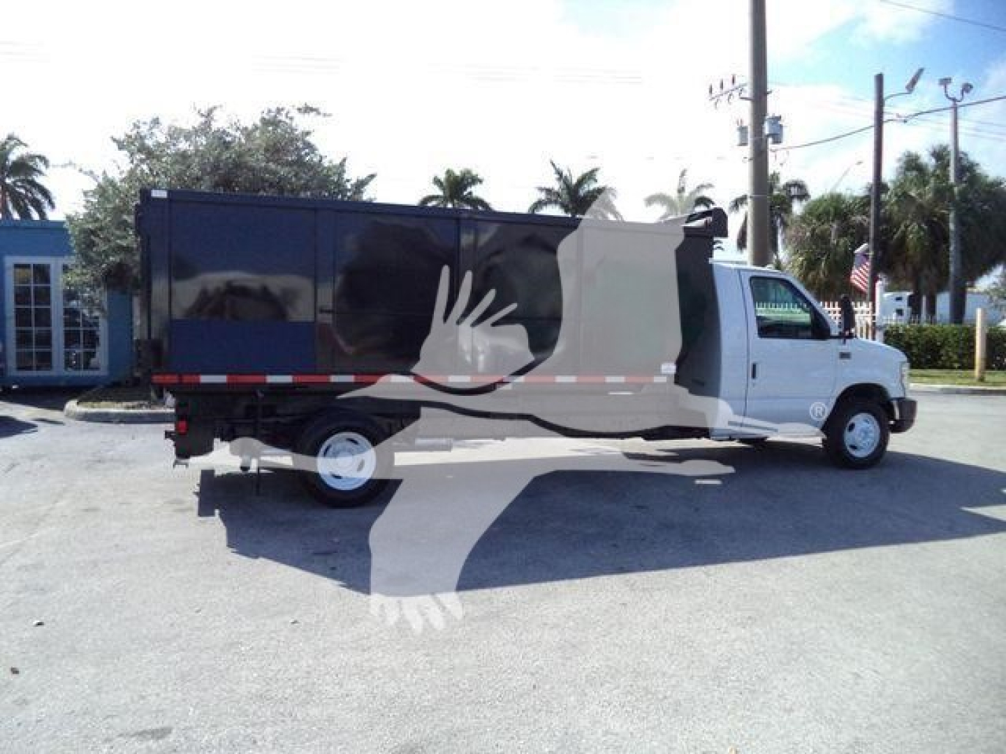 2011 Ford E450 dump truck with black dump body and white cab, side view, license plate area, in a parking lot.
