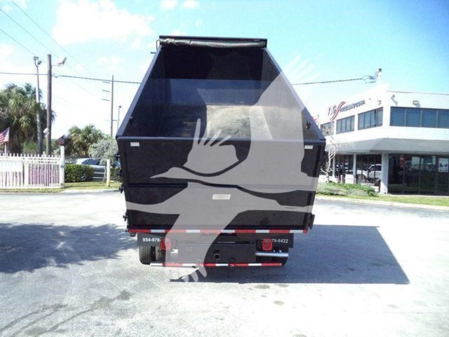 Rear view of a Ford E450 dump truck with open bed and tailgate, showing back of the dump body and bumper.