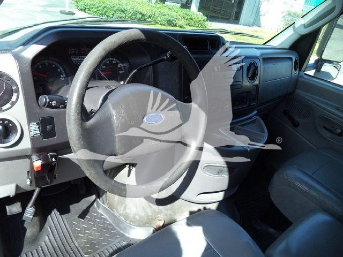Dashboard and steering wheel area of a Ford E450 truck interior showing steering wheel, gauge cluster, and vinyl seat.