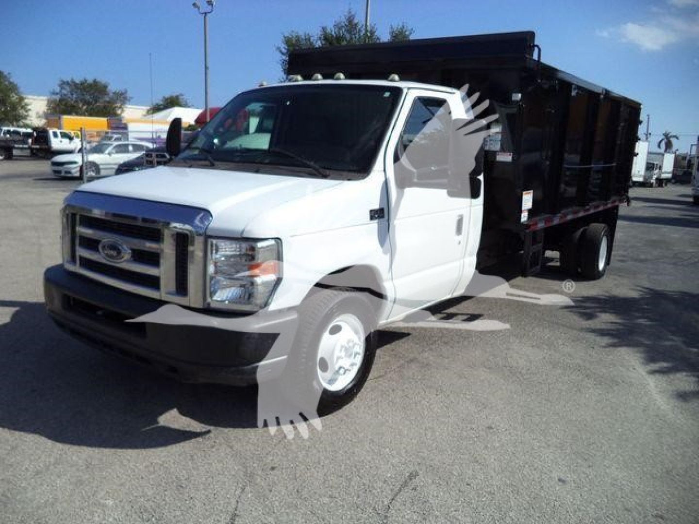 Ford E450 dump truck in white cab with black dump bed, side view showing front grille and wheel.