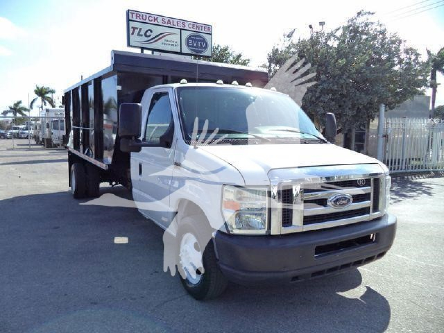 Ford E-450 dump truck with white cab and black dump bed, front view in dealership lot.
