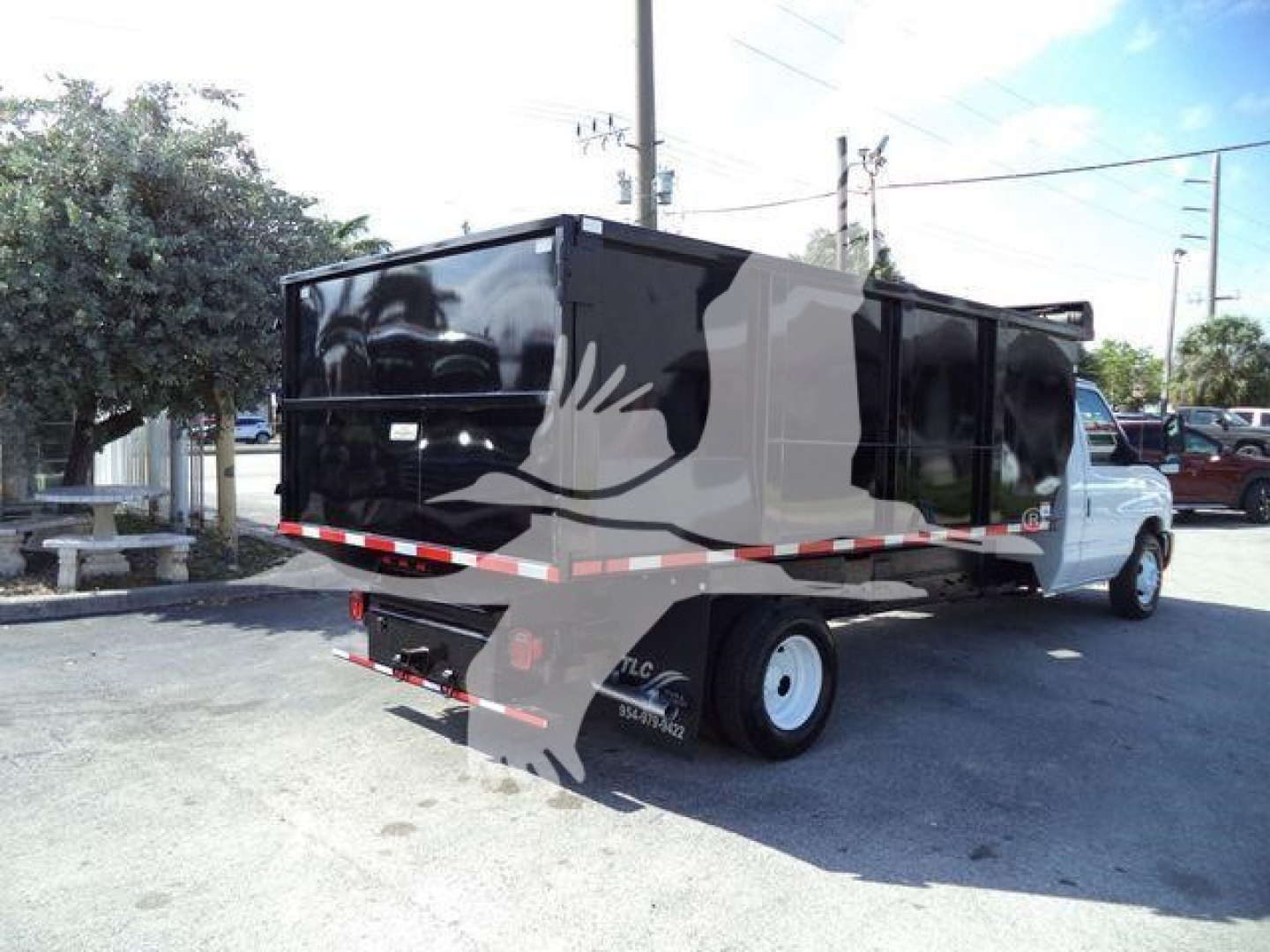 Ford Econoline E-450 dump truck rear-side view showing dump bed and black exterior with white cab
