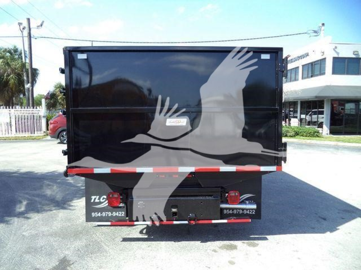 Ford E-450 dump truck rear view with black flatbed and white bird graphic, taillights on each side, red/white reflective stripe, stock number T96309FM.