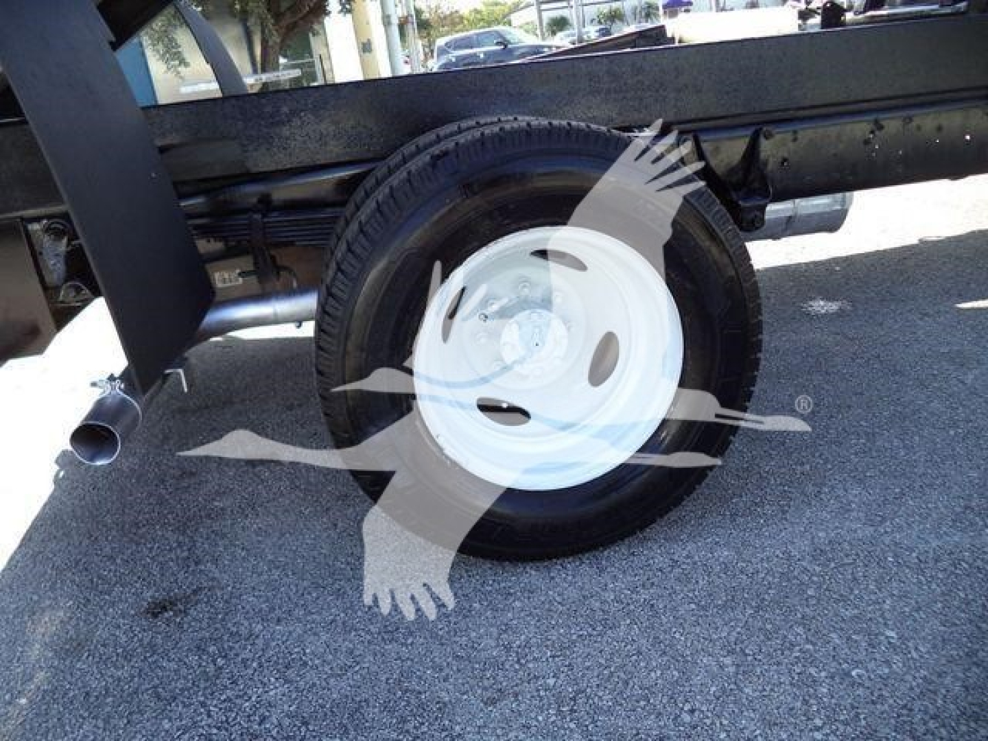 Truck wheel and undercarriage showing white steel rim and tire on a Ford E450 dump truck.