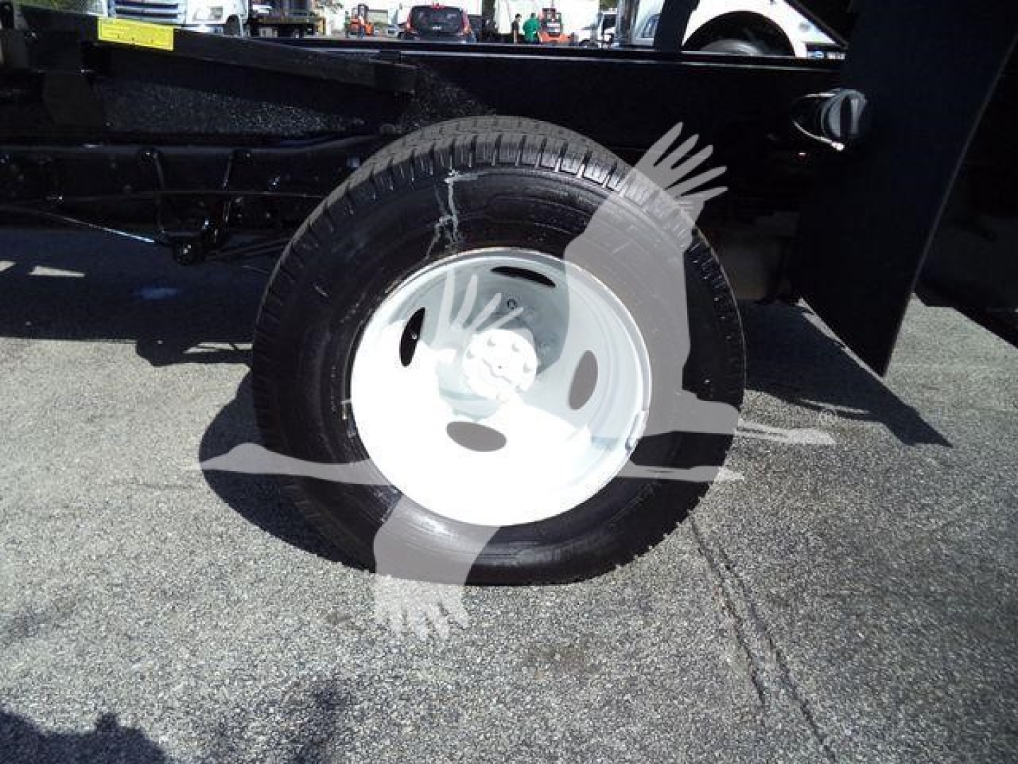 Ford E450 dump truck wheel visible, steel white hubcap with tire mounted on axle.
