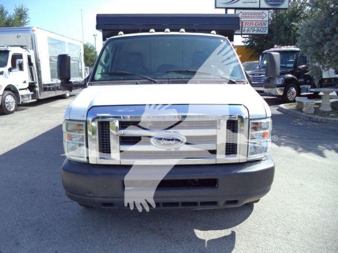 Ford E-450 front view showing large chrome grille, headlights, and black front bumper in a truck lot.