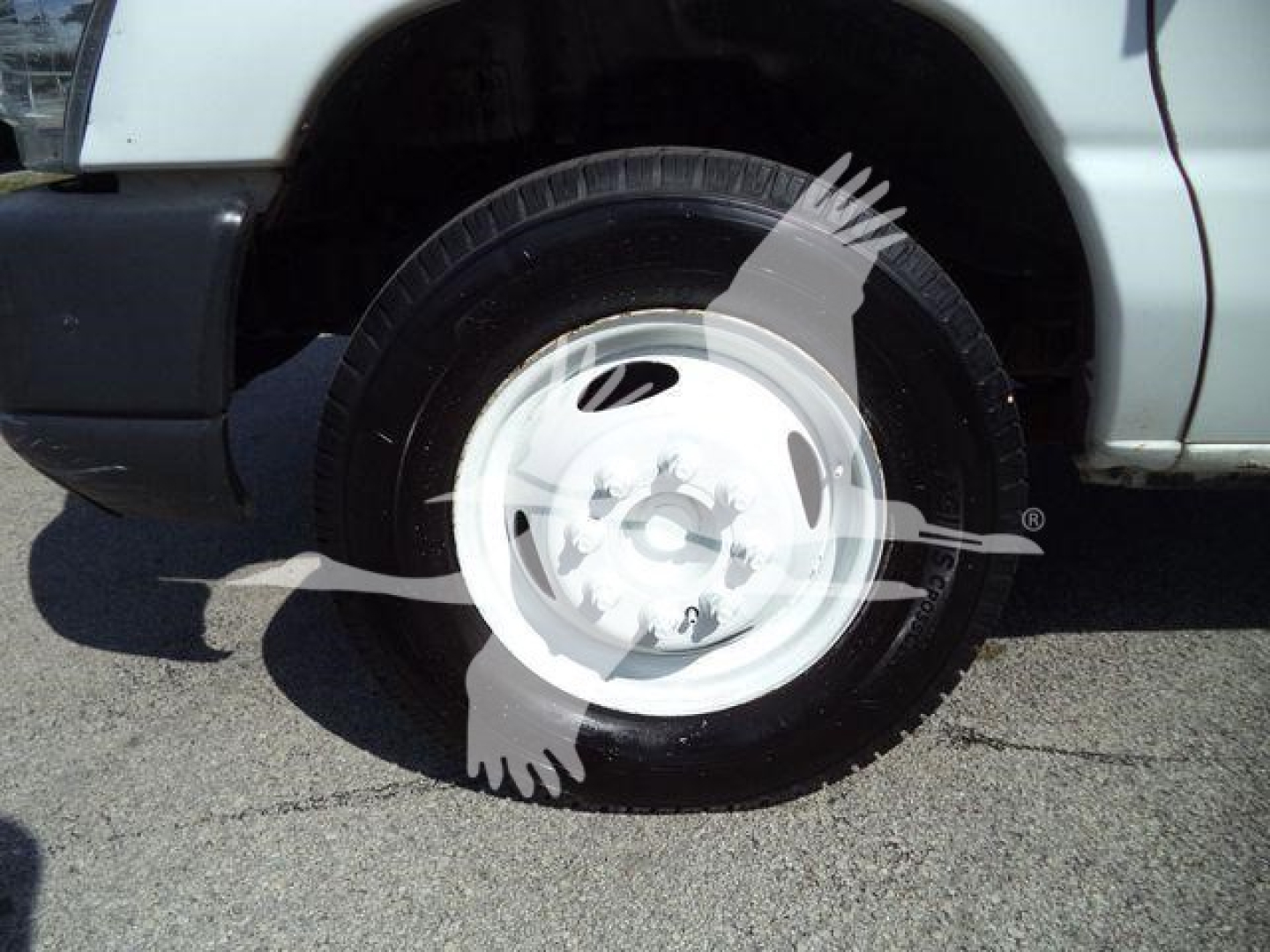 Ford E-450 front passenger wheel and tire visible in a truck bed with white wheel cover and partial fender.