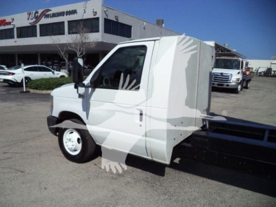 Ford E-450 chassis cab dump truck with flatbed and utility box, side view in dealership lot.