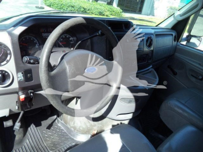 Dashboard and steering wheel area of a Ford E450 truck interior showing steering wheel, gauge cluster, and vinyl seat.