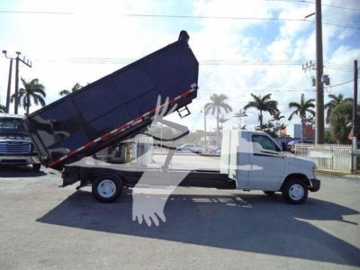 Ford E450 dump truck with a raised dump bed in-side view showing the truck bed and hoist mechanism.