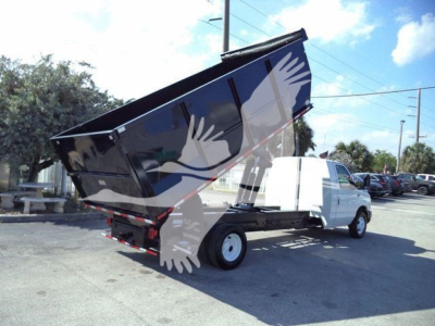Ford E450 dump truck with raised black dump bed, white cab, on a paved lot