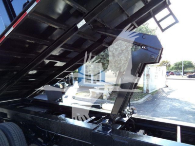 Ford E450 dump truck bed in raised position showing hydraulic system and chassis components.