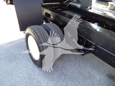 Ford E450 dump truck rear axle with dual wheels and black chassis frame visible, part of the truck’s undercarriage.