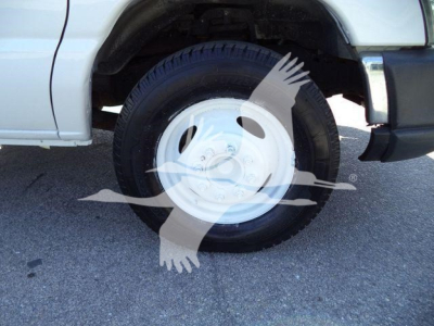 Truck front wheel well and white steel wheel on a Ford E-450 dump truck showing a basic wheel and tire.