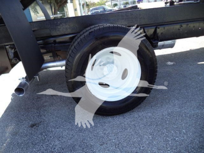Truck wheel and undercarriage showing white steel rim and tire on a Ford E450 dump truck.
