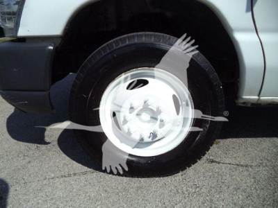 Ford E-450 front passenger wheel and tire visible in a truck bed with white wheel cover and partial fender.