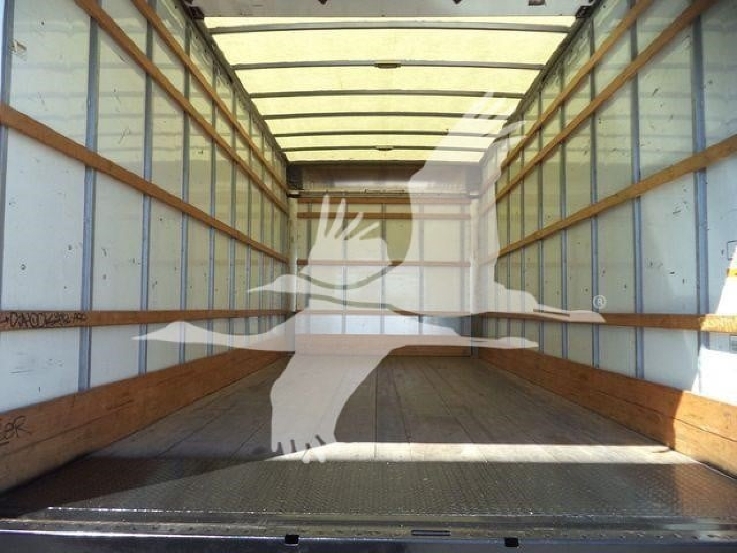 Truck cargo box interior of a 2011 Ford E450, empty wooden side rails, metal floor with grip, daylight from open rear, silhouette watermark overlay.