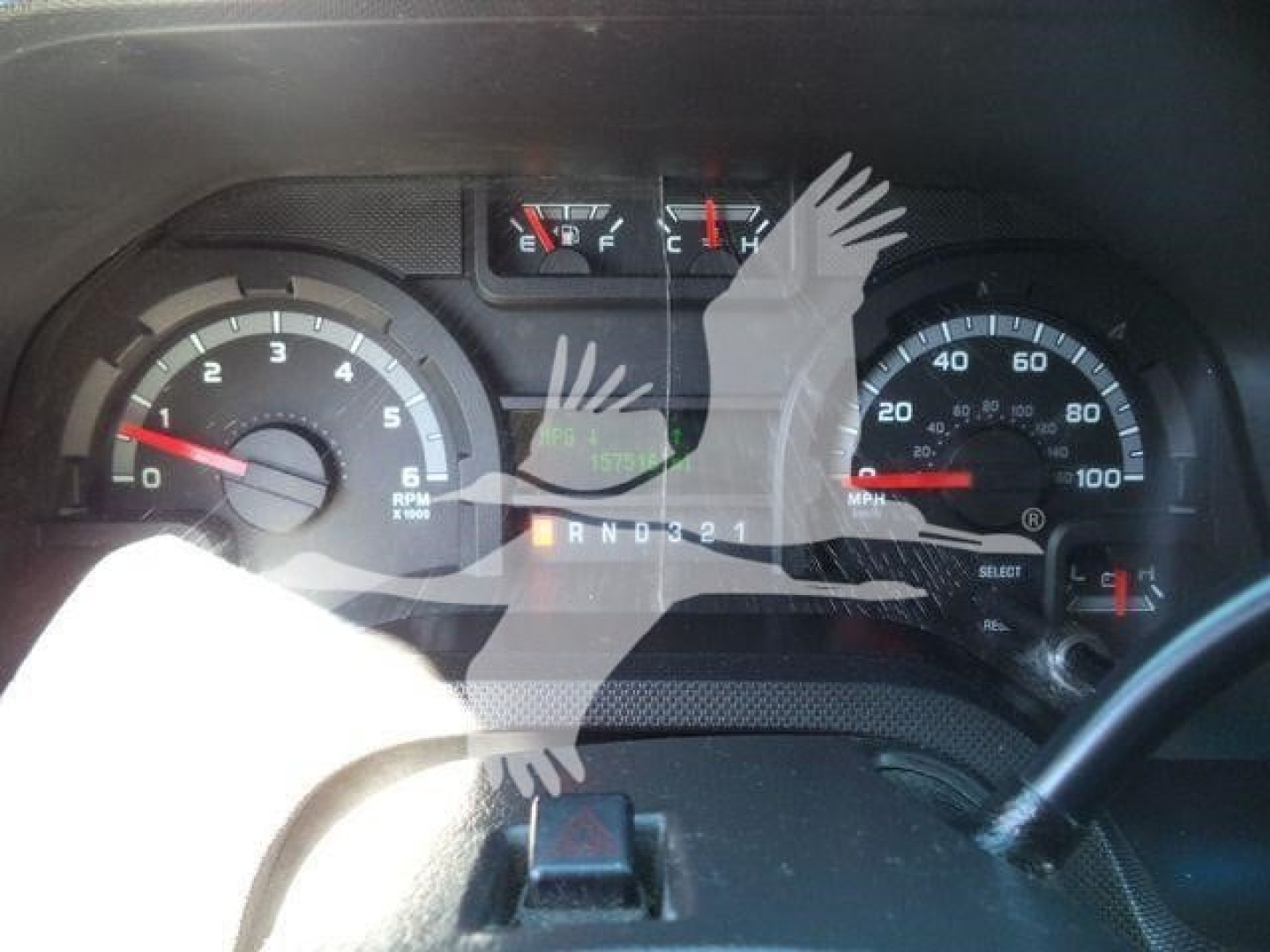 Dashboard view of a 2011 Ford E450 with tachometer, speedometer, fuel gauge, and warning lights; gear selector showing PRND321; windshield glare over the instrument cluster.
