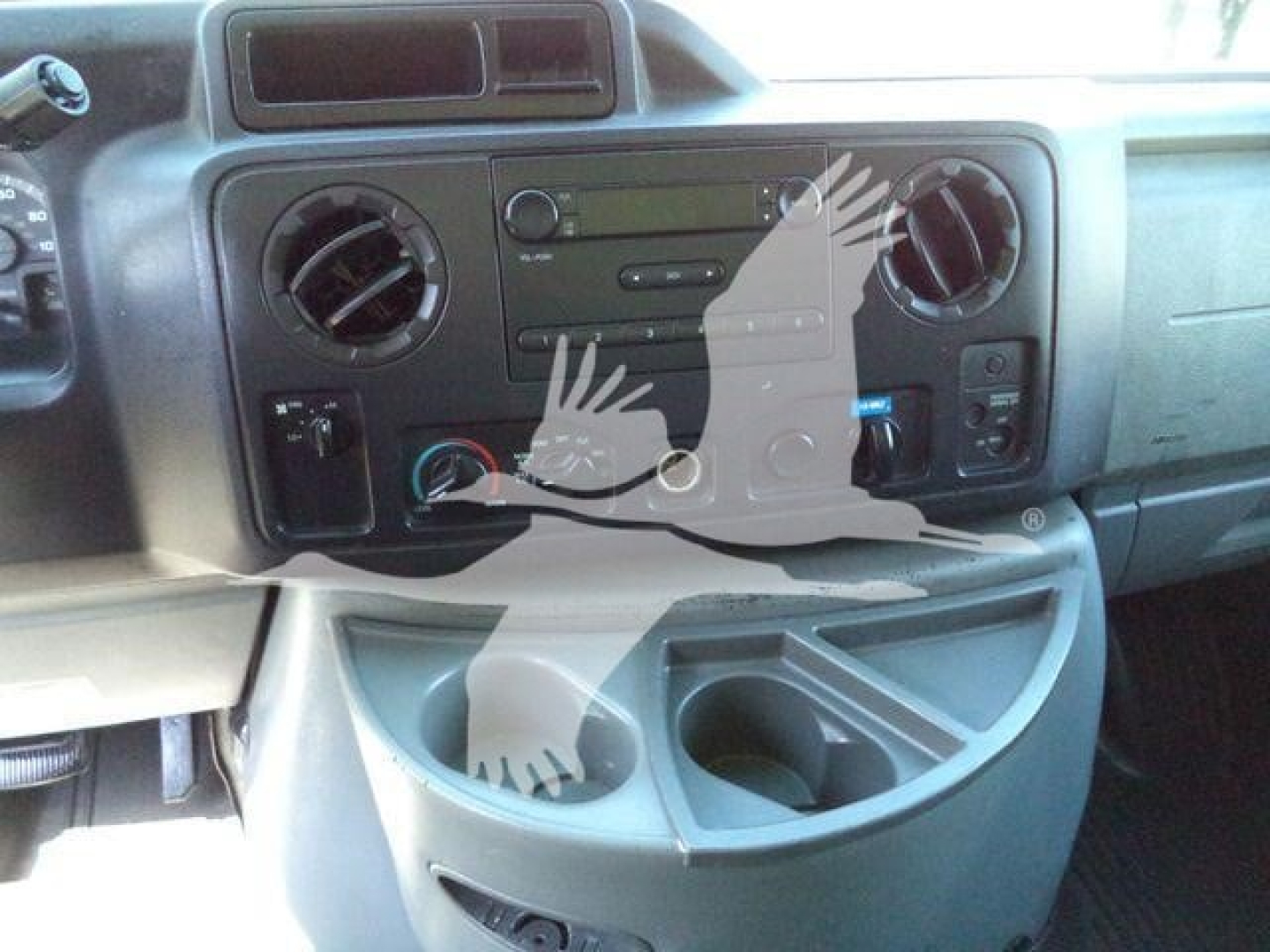 Dashboard area of a Ford E-450 cargo van showing center console with radio, climate controls, circular vents, and cup holders.
