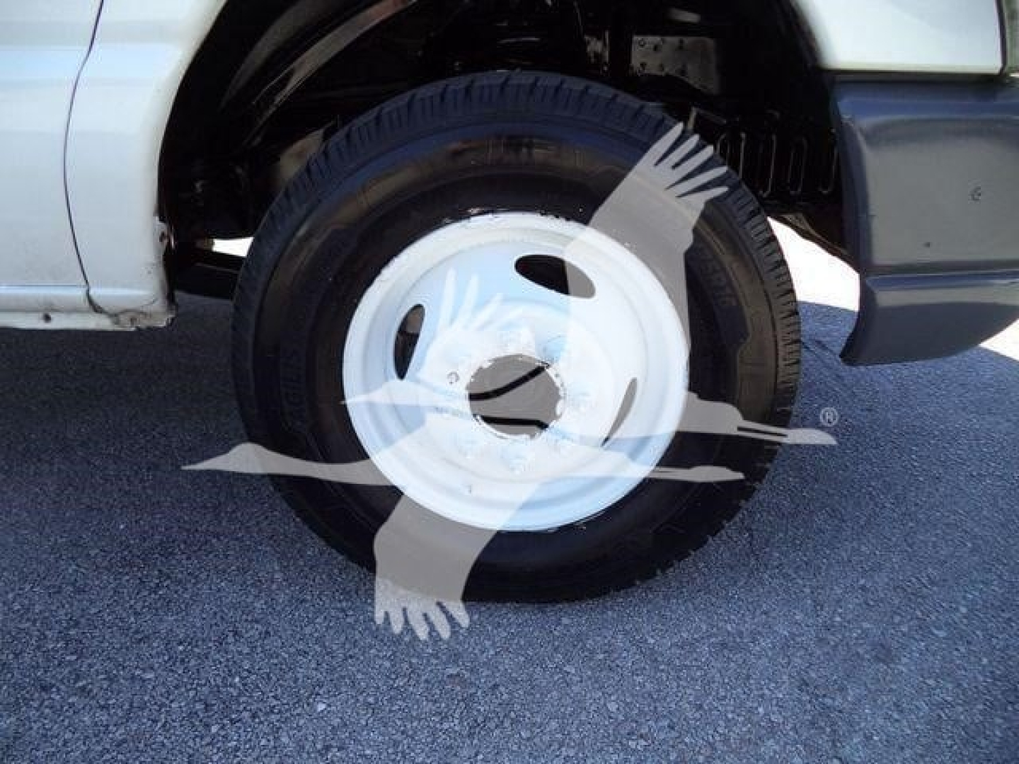 Ford E-450 chassis showing wheel and tire, white steel wheel cover, partial fender and front door area