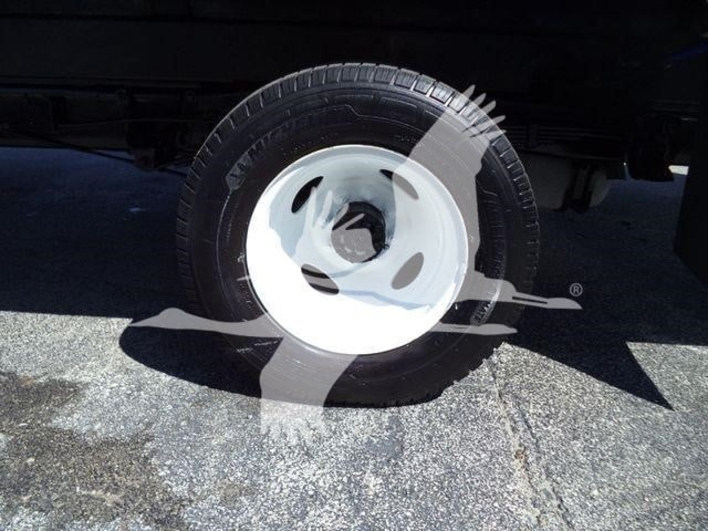 Ford E-450 box truck wheel and tire view showing steel wheel and tire with side shadow.