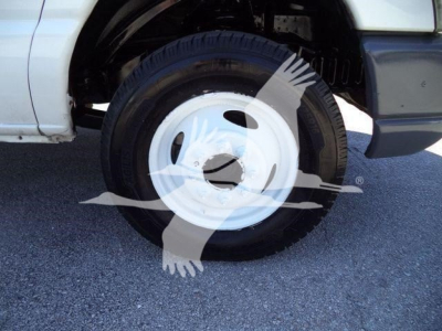 Ford E-450 chassis showing wheel and tire, white steel wheel cover, partial fender and front door area
