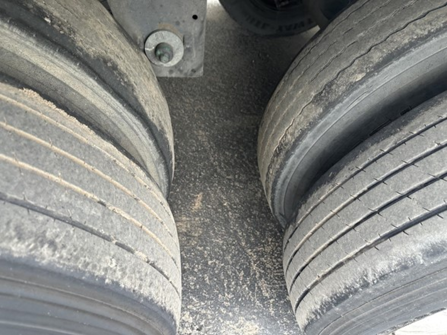 Trailer axle area showing two rear dual tires with wear marks and grime on dry van trailer undercarriage