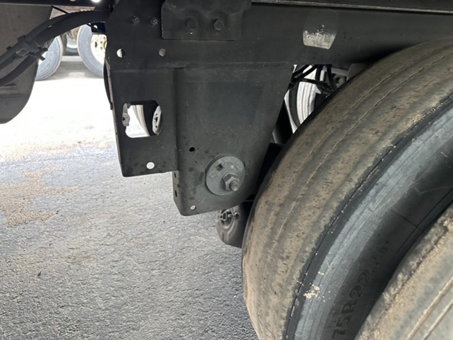 Trailer undercarriage and large dual rear wheel showing structural brackets and mounting bolt.