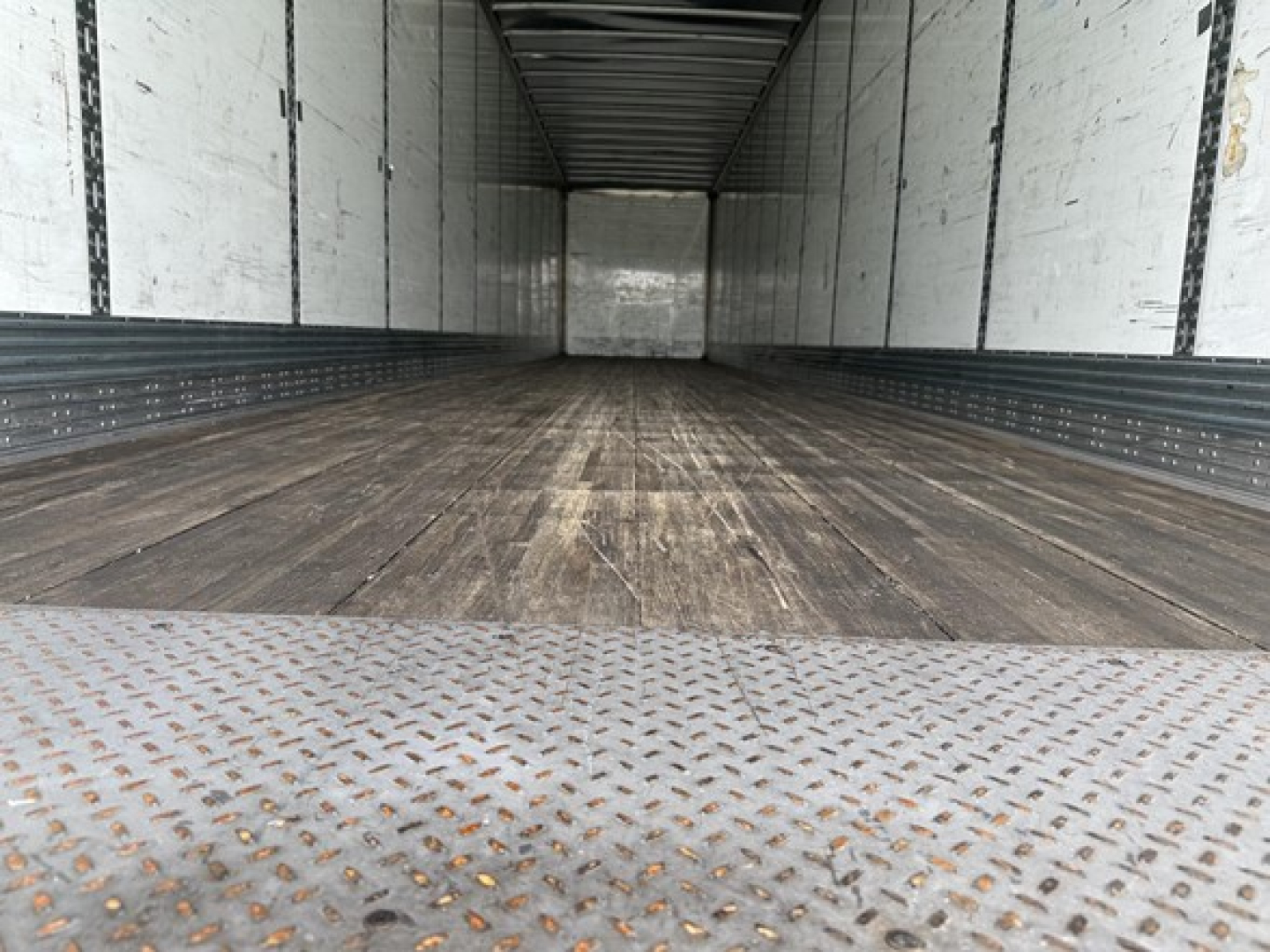 Inside of a 2022 Wabash Duraplate 53' air ride dry van trailer with wooden floor, metallic side walls, and rear opening. No text visible.