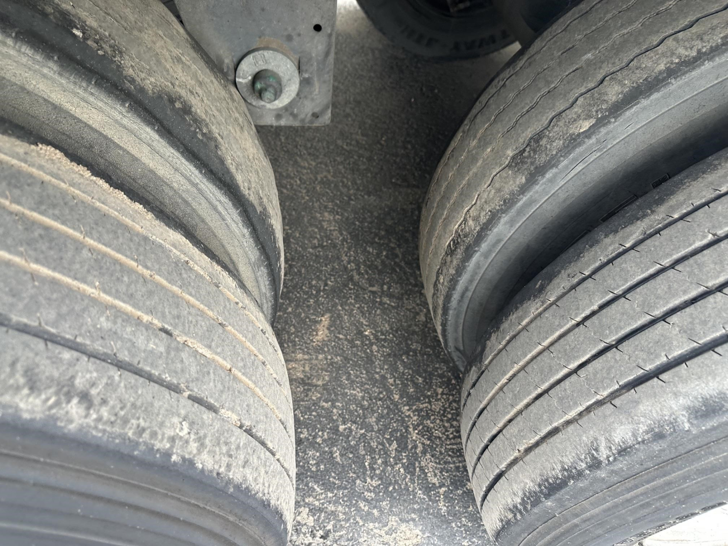 Wabash Duraplate trailer dual tires showing worn tread, road grime, and center clearance with suspension components.